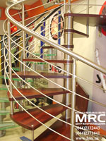 Baluster from polished stainless steel of winding staircase with oak stages